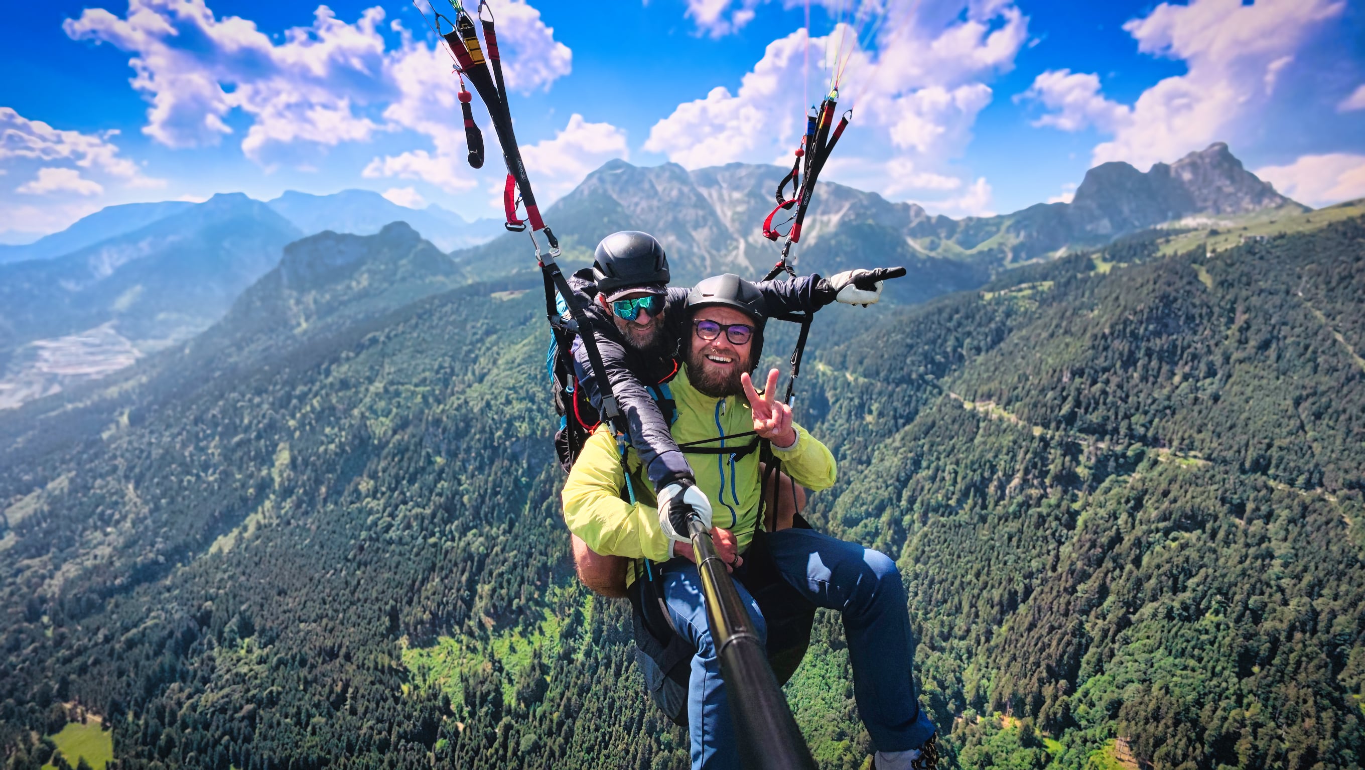 Zwei Männer beim Tandem-Paragliding über Berglandschaft